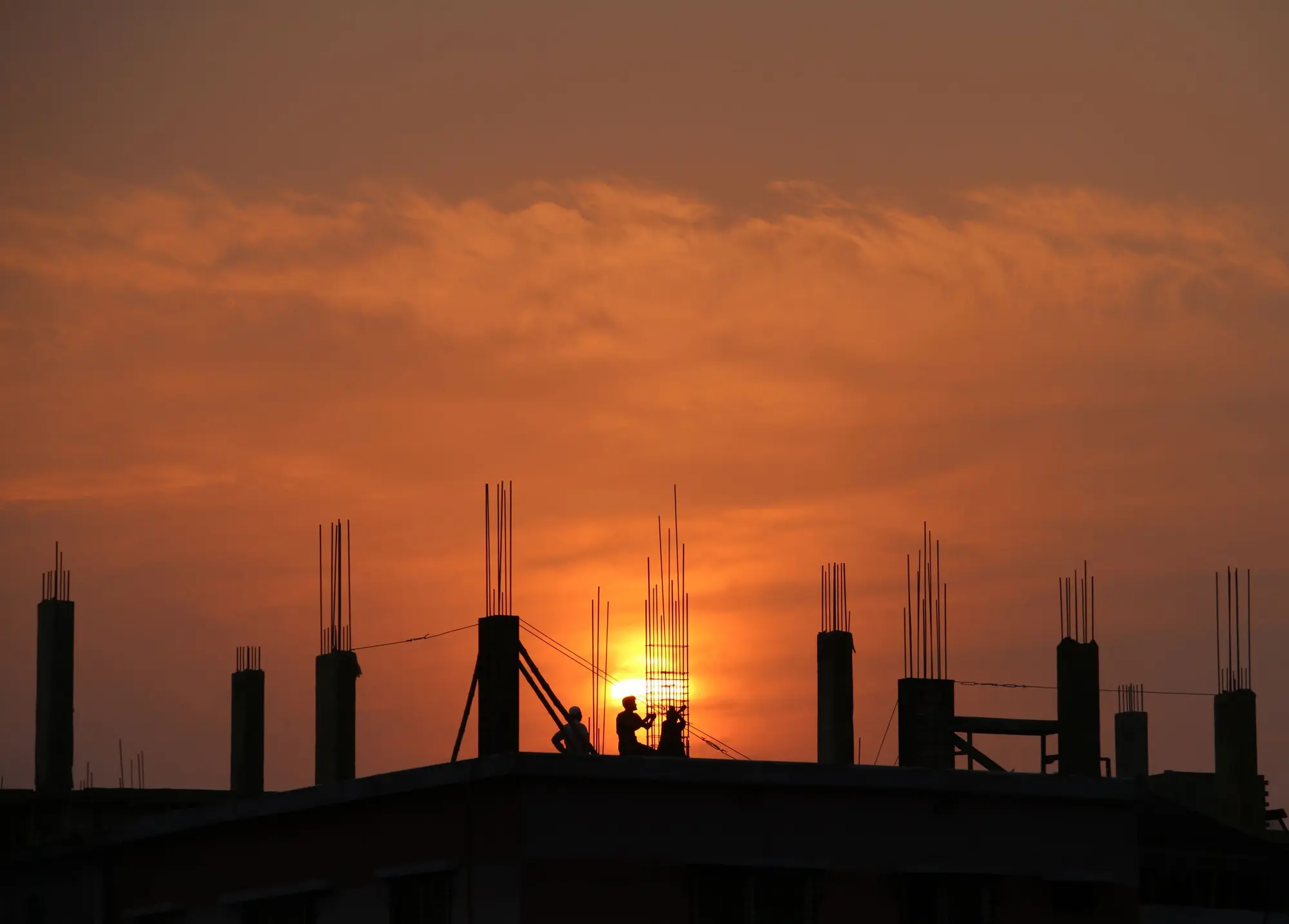 Silhouettes of tradies on a construction site at sunset.